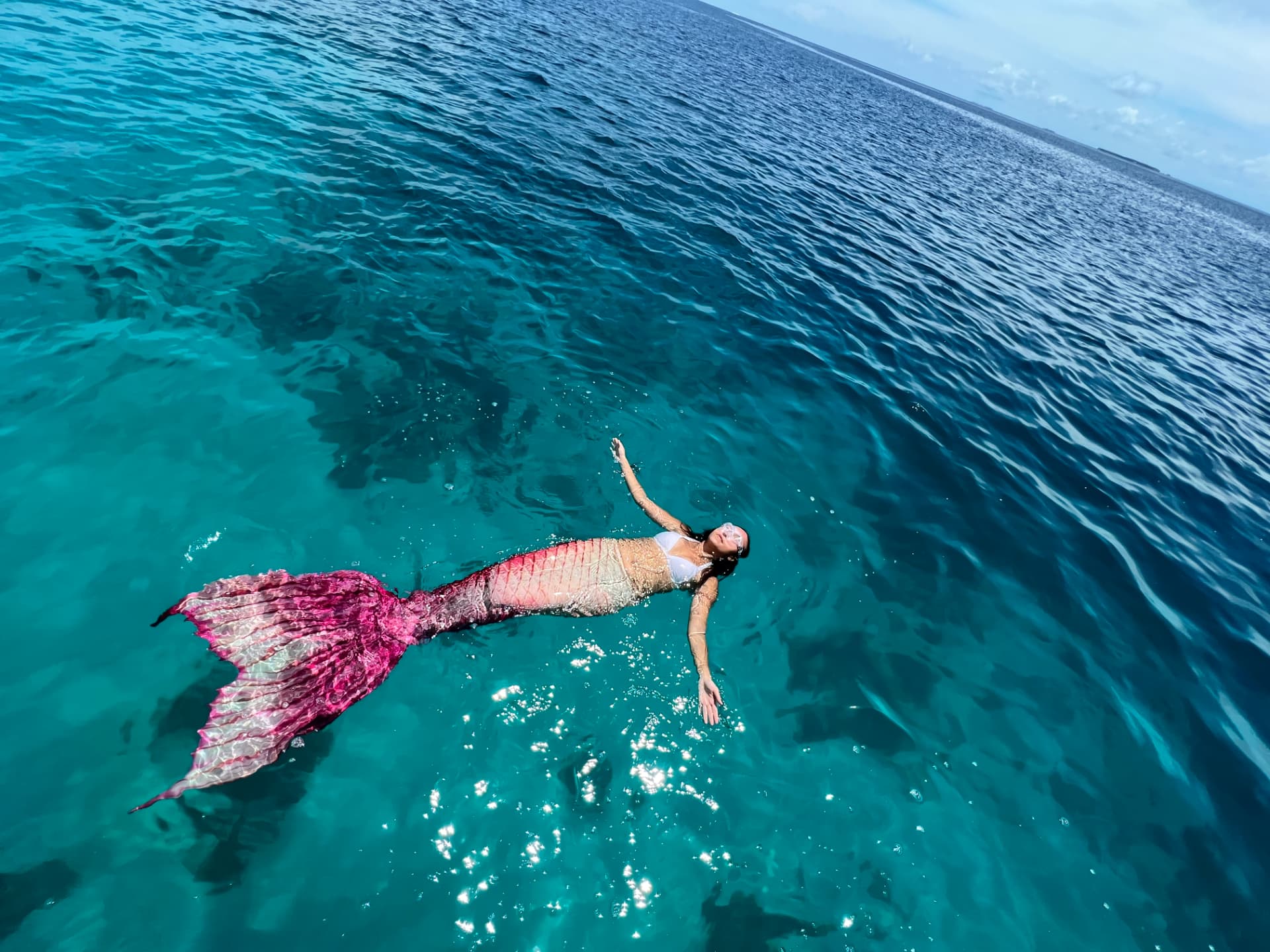 Angelia floating in the ocean in a pink tail